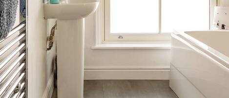 A bathroom with a white sink, a window, and a bathtub.