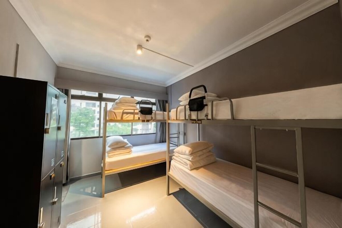 Habitación tipo dormitorio con literas, un armario y una ventana.