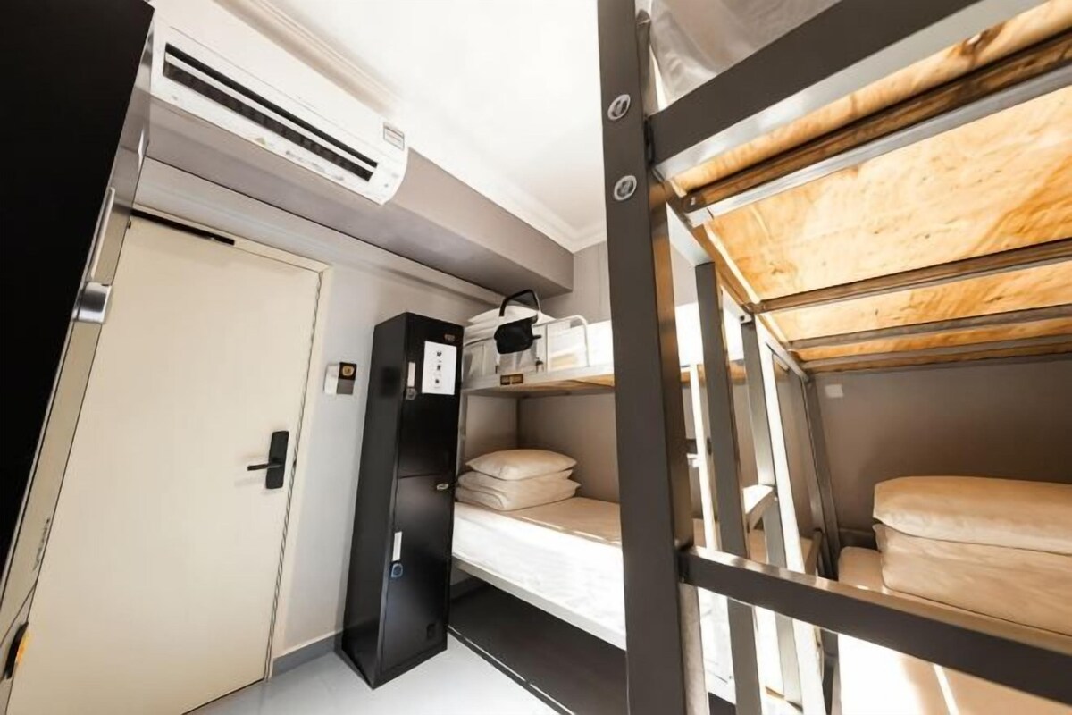 A compact train compartment with bunk beds, a small kitchenette, and a door.