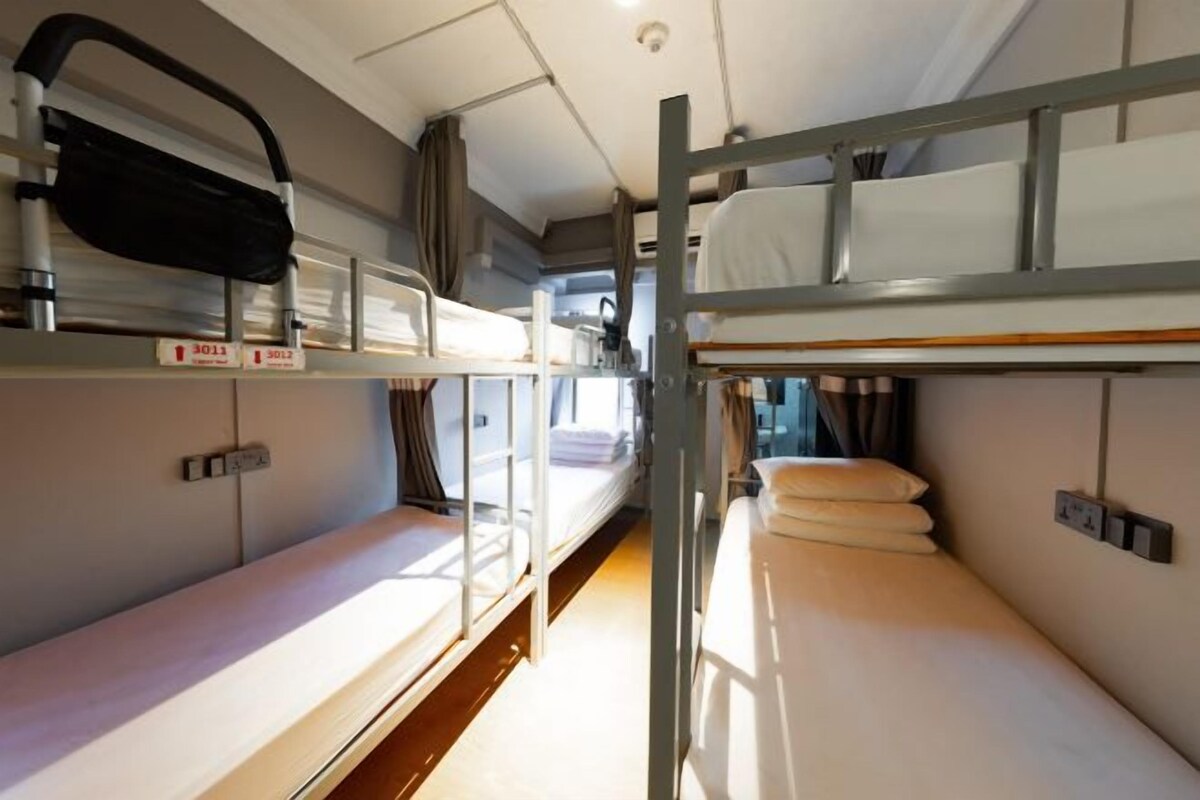 A bunk bed room with a window, a headboard, and a bedside table.