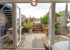 A covered patio with a wooden deck, outdoor furniture, potted plants, and a staircase leading to an upper level. - Seadream - Seadream Scarborough Limited (Scarborough)