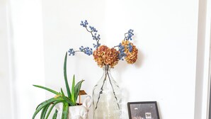 Une table en bois ornée d’un vase de fleurs, d’un tableau encadré et d’une petite plante.