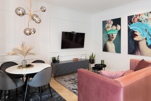 A modern living room with a round dining table, grey chairs, a pink sofa, a grey console table, and a flat-screen TV mounted on the wall. - Candy Ballerina I-IV Zagreb Center Lux (Zagreb)