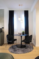 Een eetgedeelte met een ronde tafel, twee stoelen, een kleine plant en een kroonluchter.