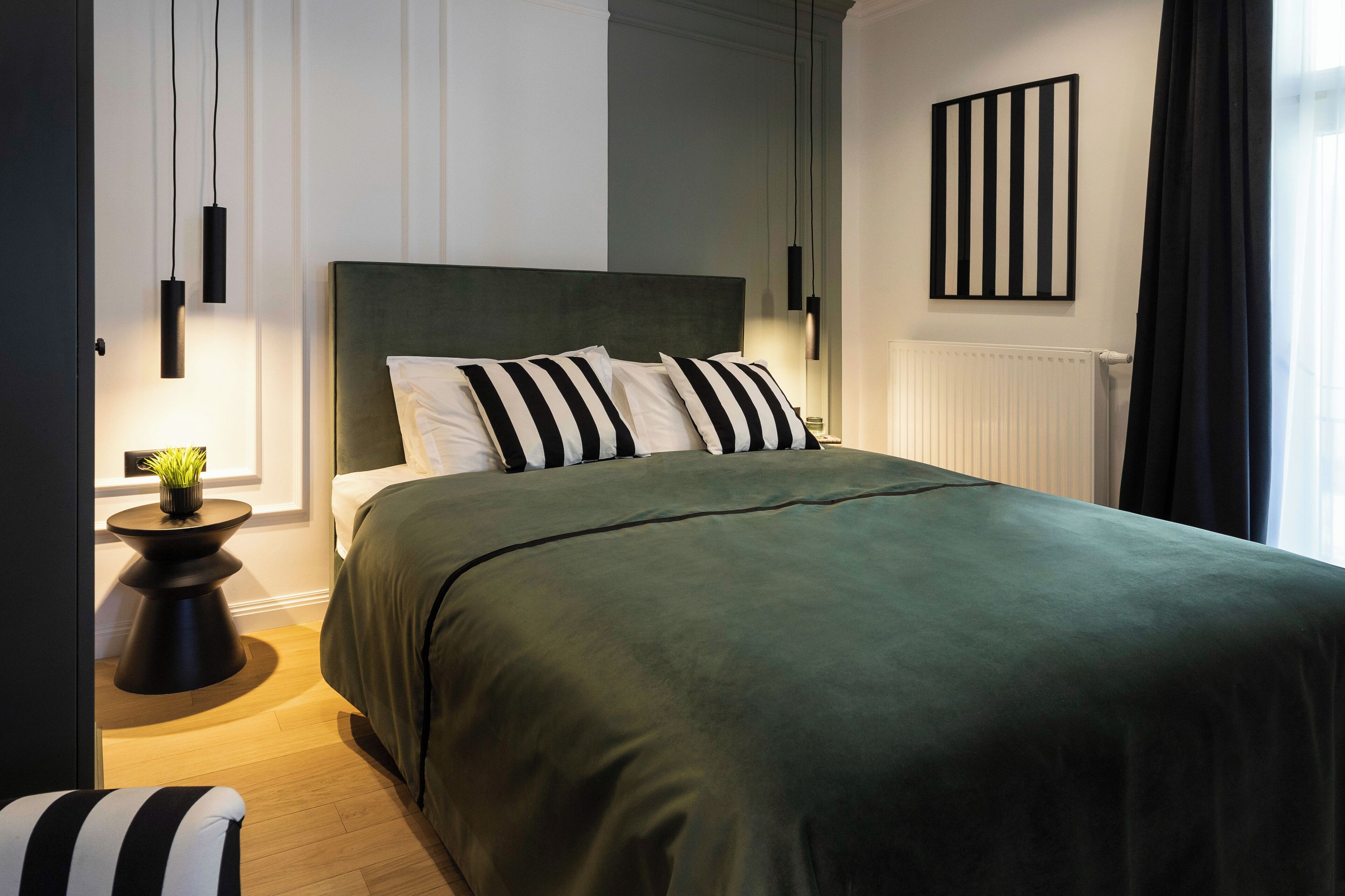Un dormitorio moderno con una cama grande, una mesita de noche con lámpara y un radiador.