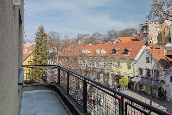A balcony with a tiled floor, a metal railing, and a view of colorful buildings with red roofs. - Candy Ballerina I-IV Zagreb Center Lux (Zagreb)