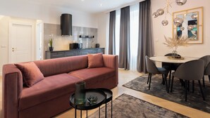 Una sala moderna con un sofá, una mesa de comedor con sillas, una zona de cocina y un ventanal con cortinas.