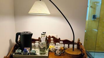 A wooden tray with a coffee maker, a bottle of water, and several glass jars on a table.