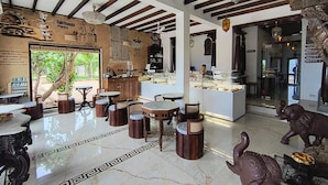 A bakery with marble floors, wooden furniture, and a self-service display. - La Plage SeaView Suites (Puducherry)