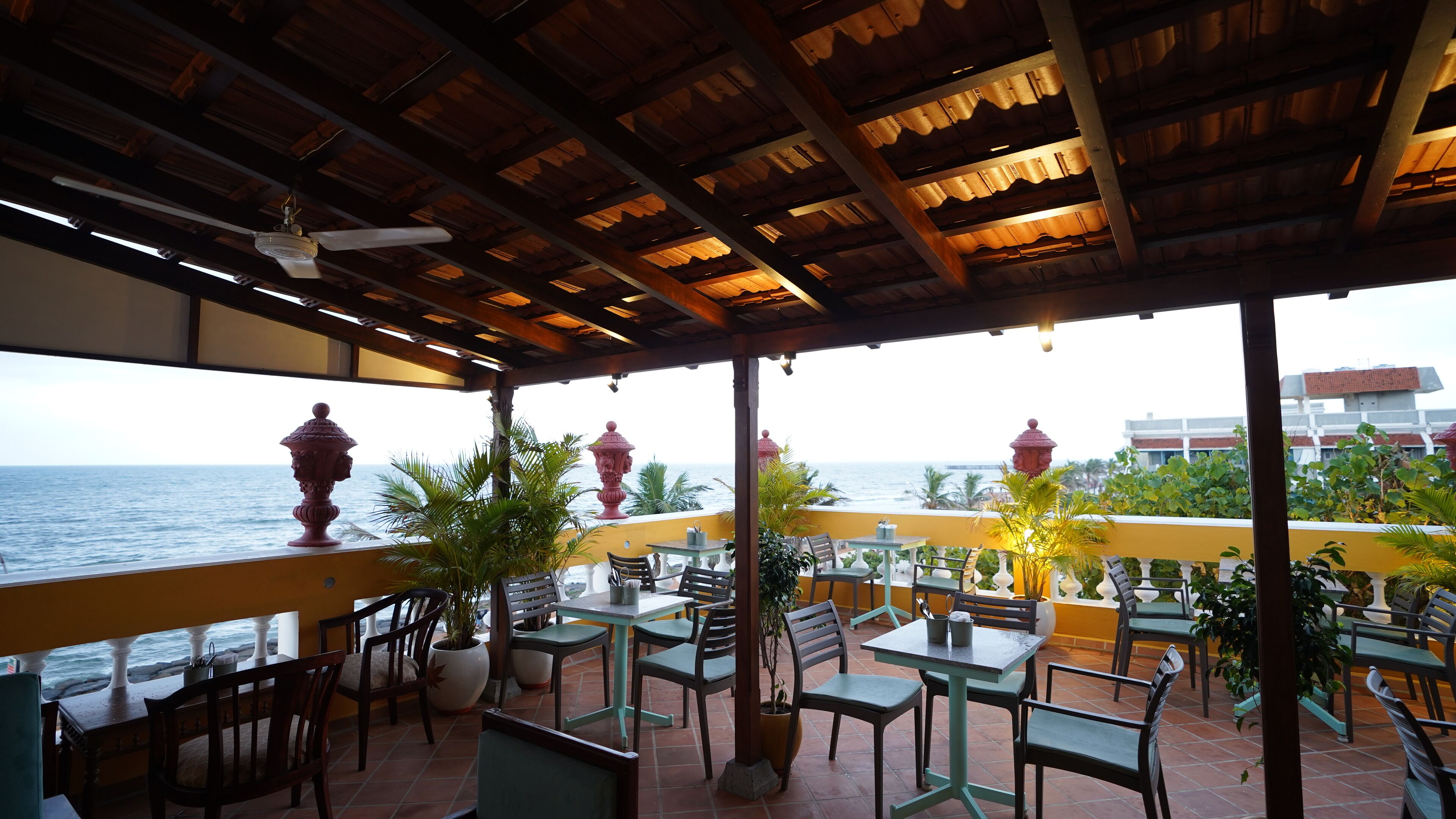 An outdoor patio with tables and chairs, overlooking the sea.