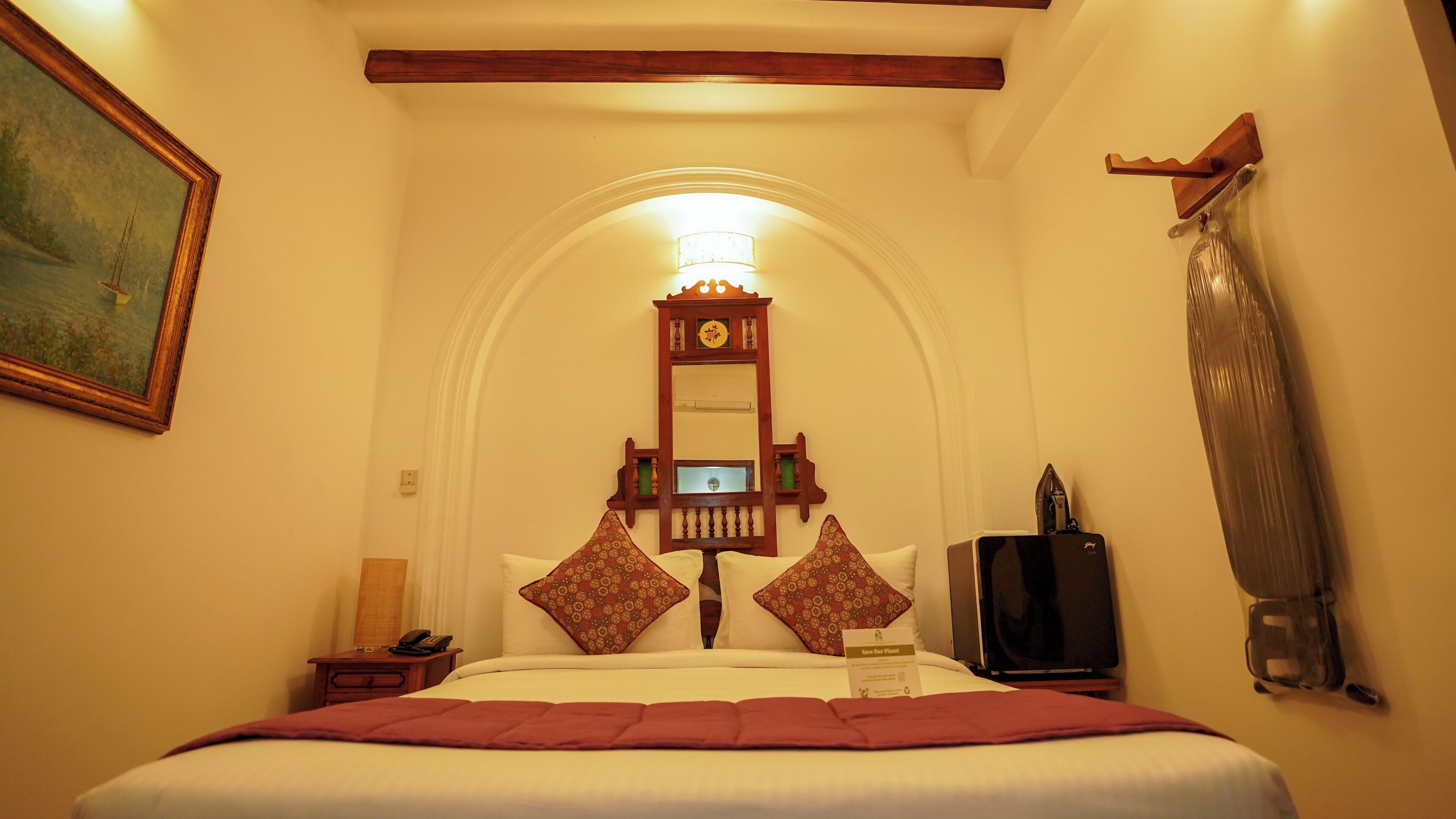 Ein Hotelzimmer mit Bett, Nachttisch, Telefon, Spiegel und Fernseher.