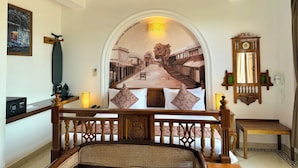 A room with a bed, a wooden bench, a wall-mounted clock, and a ceiling fan. - La Plage SeaView Suites (Puducherry)