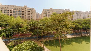 A residential area with multi-story buildings, trees, and a green lawn. - Maison Privee - Elegant Coastal Apt on Palm Jumeirah (Dubai)