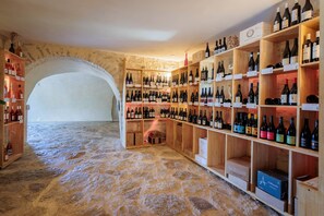 A wine cellar with stone walls, wooden shelves, and various wine bottles.