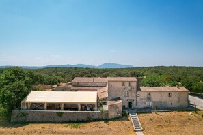 A building with a stone wall, a covered outdoor seating area, and a view of the surrounding landscape.