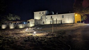 En historisk bygning med flere etager, en stenvæg og en trappe, der fører op til indgangen.