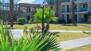 A modern hotel with a central courtyard, palm trees, and a clear blue sky. - Mare Alba (Bodrum)