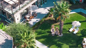 An aerial view of a hotel courtyard with outdoor seating, palm trees, and a pool. - Mare Alba (Bodrum)