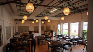 A restaurant with multiple tables and chairs, a counter area, and hanging lights.