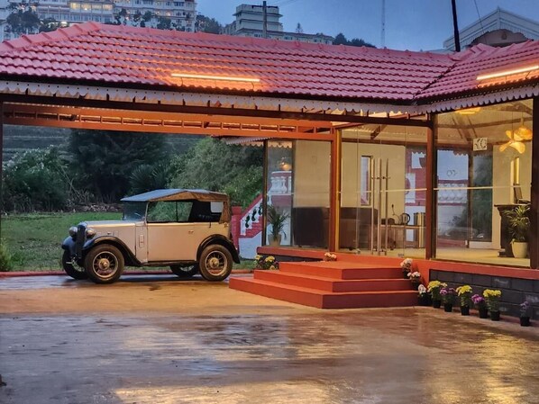 A vintage car parked in front of a building with a red-tiled roof and a glass entrance. - Welbeck Vintage by Oxygen Resorts (Ooty)