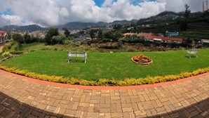 A park with a paved walkway, benches, and a grassy area with flowers.