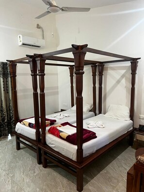 Een hemelbed met houten frame en witte beddengoed.