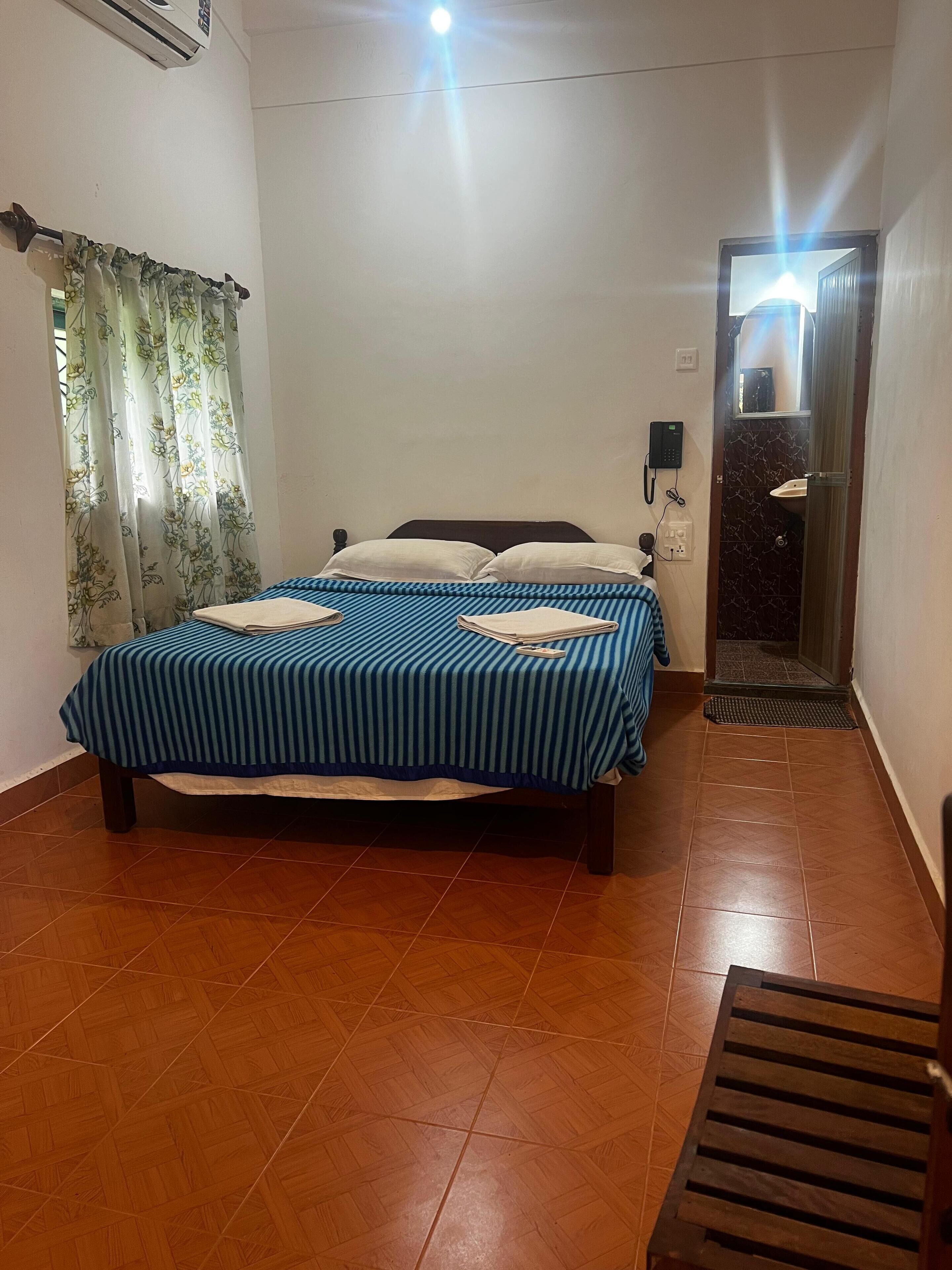 A bedroom with a bed, a telephone, and a bathroom door.
