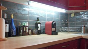 Una cocina con armarios rojos, una encimera y varias botellas y electrodomésticos.
