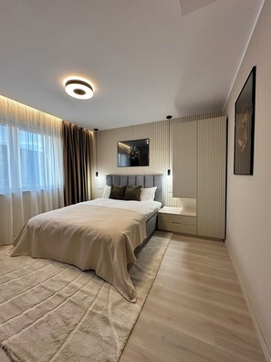Relax in this serene bedroom with a large bed, mirror, and sheer curtains.