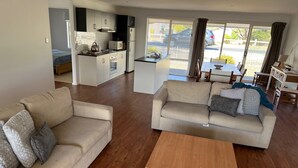 Amplia sala de estar con dos sofás, una mesa de centro de madera, una kitchenette y un comedor con vistas.