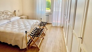 A bedroom with a bed, a radiator, a window with sheer curtains, and a wardrobe. - Fully Renovated Accomodation (Fiumicino)