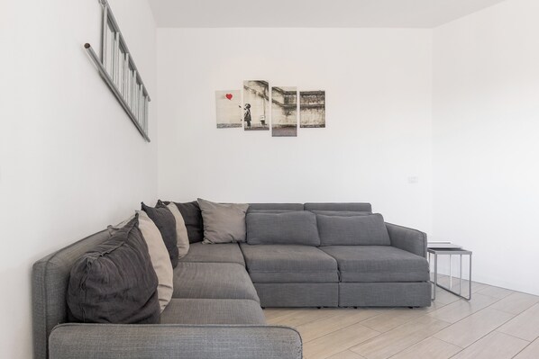 A modern living room with a grey sectional sofa, a small side table, and a wall-mounted radiator.