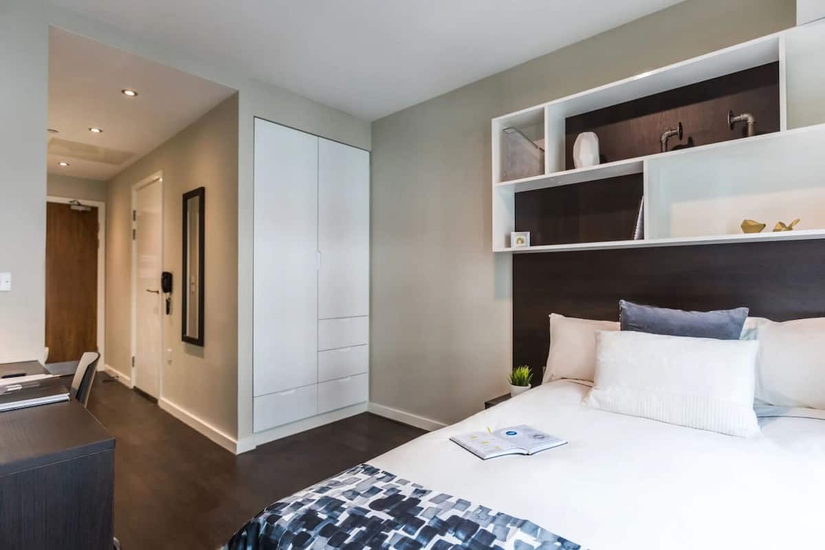 A modern bedroom with a bed, a desk, and a wardrobe.