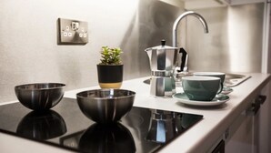 Une cuisine moderne avec une plaque de cuisson noire, une machine à café et deux bols posés sur le comptoir.