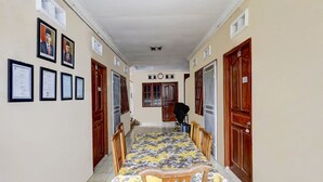A corridor with a dining table and chairs, framed certificates on the wall, and wooden doors. - Hotel O Manisee 1 Homestay Syariah (Batam)