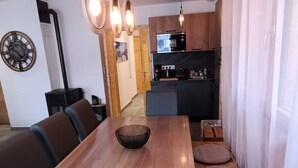 A dining area with a wooden table and chairs, a kitchen in the background, and a clock on the wall. - Apartment Vars, 2 bedrooms, 7 persons (Vars)
