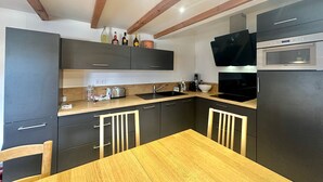 A modern kitchen with dark cabinets, a wooden table, and a built-in oven.