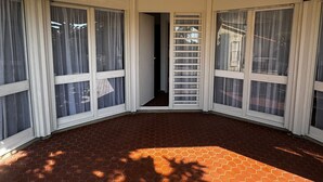 Ein Eckzimmer mit Backboden, großen Fenstern mit weißen Rahmen und einer Tür zu einem anderen Raum.