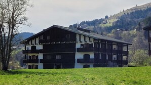 A traditional chalet-style building with multiple balconies, set against a backdrop of a mountainous landscape.