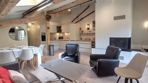 A modern living room with a glass coffee table, leather sofas, and a dining area with a round table and chairs.