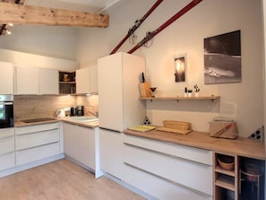 A modern kitchen with white cabinets, a wooden countertop, and a built-in oven.