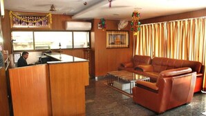 A hotel lobby with a reception desk, leather sofa, and a coffee table. - Shri Valli Resdiency (Chennai)
