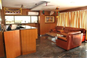 A hotel lobby with a reception desk, leather sofa, and a coffee table. - Shri Valli Resdiency (Chennai)