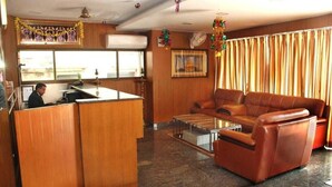 A hotel lobby with a reception desk, leather sofa, and a coffee table. - Shri Valli Resdiency (Chennai)