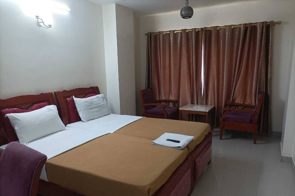 A hotel room with a bed, a desk, two chairs, a table, and a curtain.