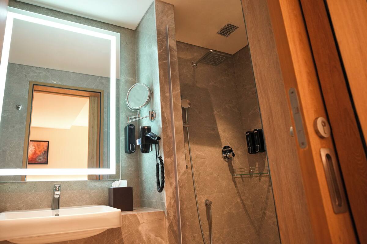 A bathroom with a sink, mirror, and shower area.