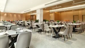 A spacious dining area with multiple tables and chairs, a modern ceiling design, and a clean, well-lit environment. - Home Inn Wanxin Ruibo Hotel  (Beihai)