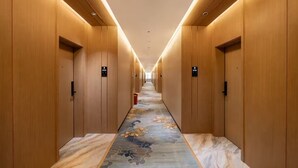 A hallway with wooden paneling and a patterned carpet, leading to a door at the end. - Home Inn Wanxin Ruibo Hotel  (Beihai)
