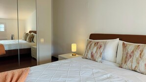 Habitació d'hotel amb llit, tauleta de nit, làmpada i mirall.