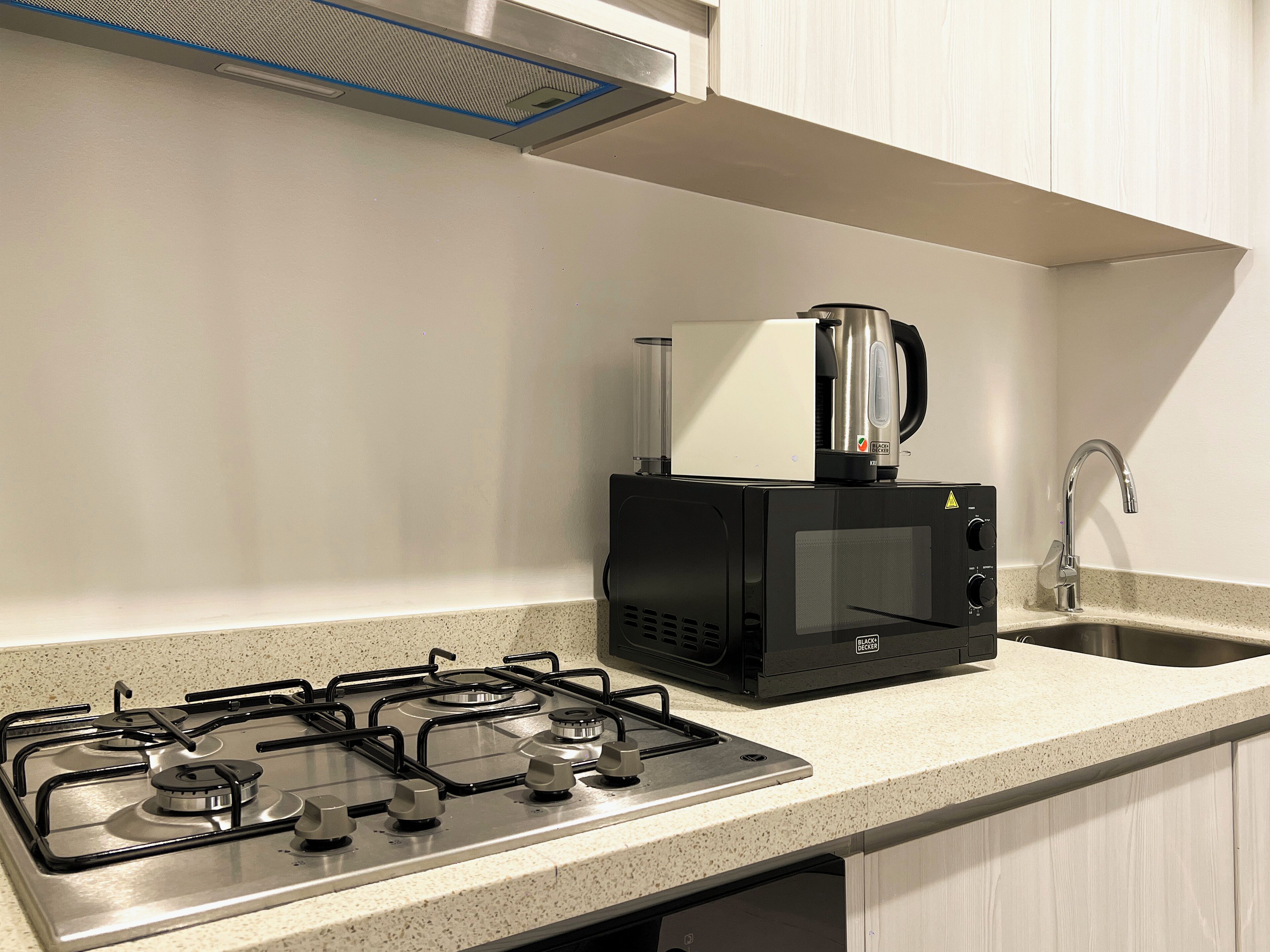 A kitchen with a gas stove, a microwave, and a coffee maker on the countertop.